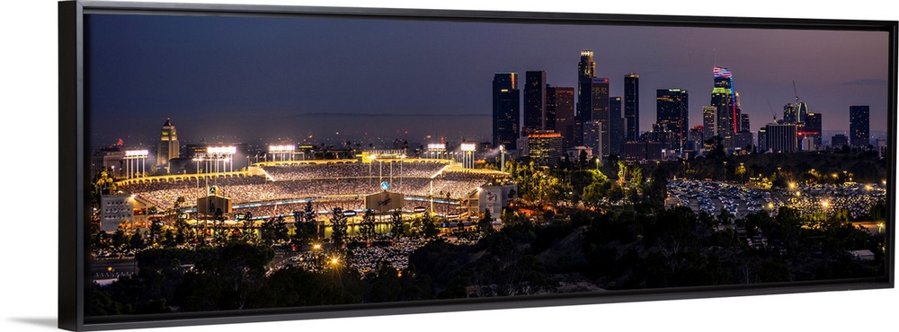 Panoramic photograph of Dodger Stadium lit up on a game night with the Los Angeles skyline on the right.