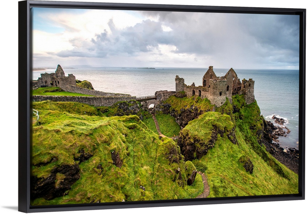 Landscape photograph of Dunluce Castle next to the ocean, taken from a higher point.
