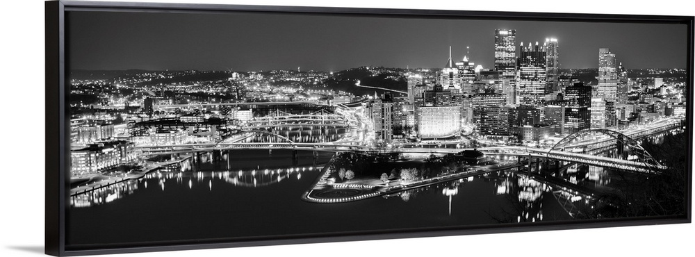 Panoramic photo of the city of Pittsburgh illuminated at night, with Point State Park in the foreground.