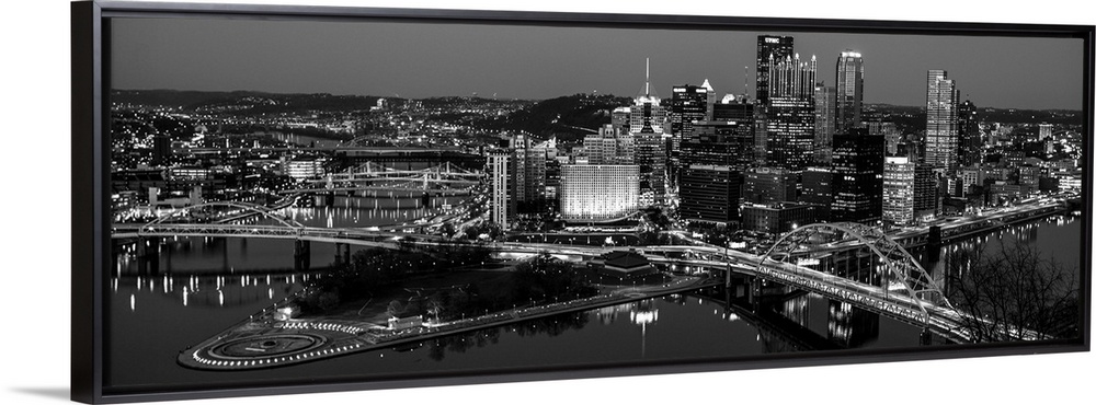 Panoramic photo of the city of Pittsburgh illuminated at night, with Point State Park in the foreground.