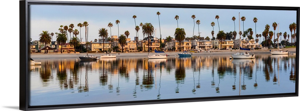 Panoramic photograph of beach houses, palm trees, and boats on the San Diego coast reflecting into the water.