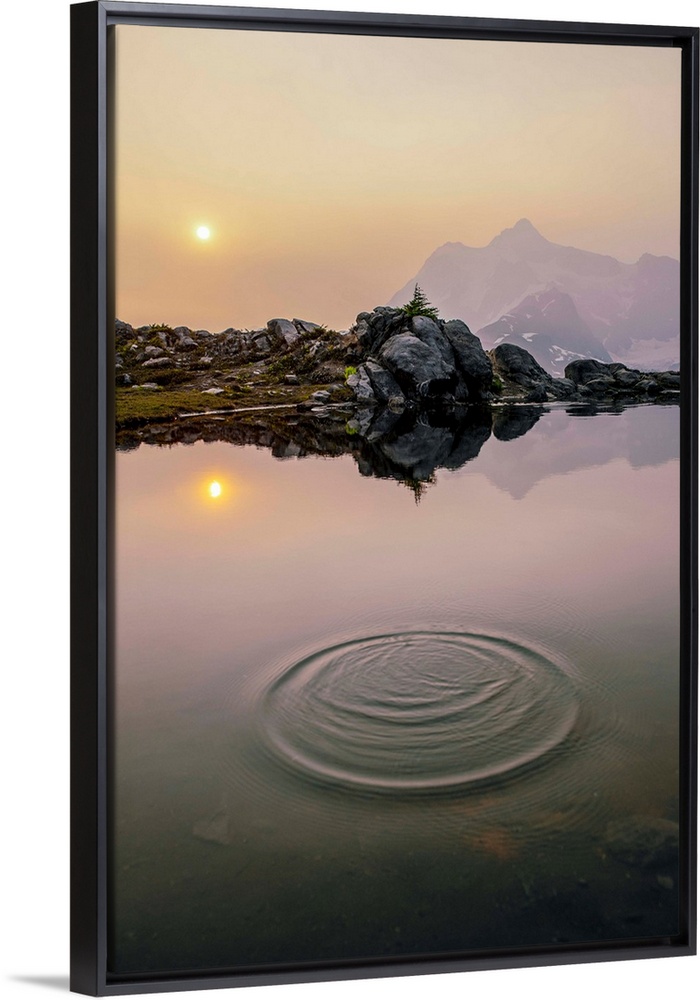 A ripple on a pond near Artist Point Trail with the sun rising over Mount Shuksan in the background, Washington.
