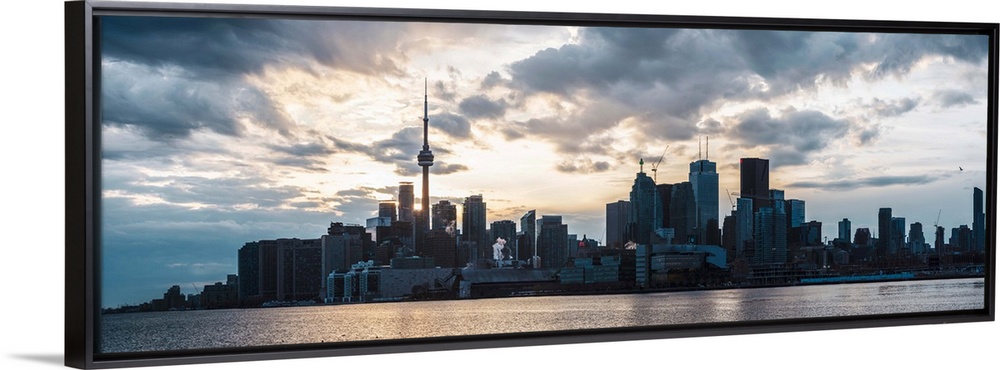 Toronto city skyline under a dramatic sunset with clouds overhead, Ontario, Canada.