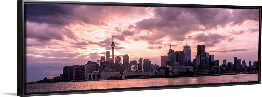 Toronto city skyline under a dramatic sunset with clouds overhead, Ontario, Canada.