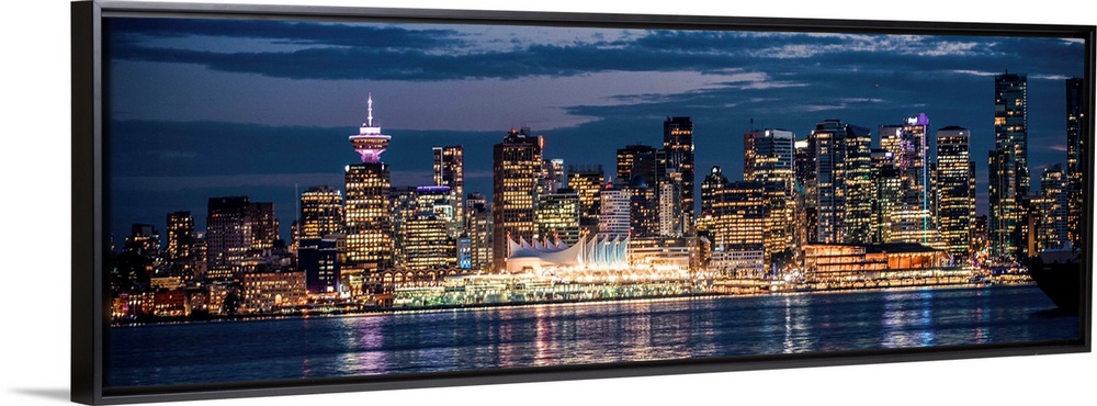 Panoramic photograph of the Vancouver, British Columbia skyline lit up on a dark blue night and reflecting bands of colorf...