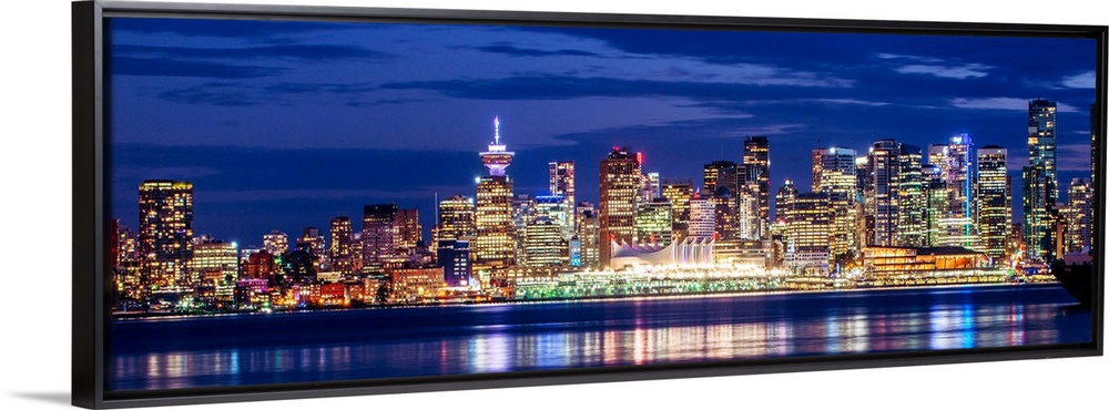 Panoramic photograph of the Vancouver, British Columbia skyline lit up on a dark purple night and reflecting bands of colo...