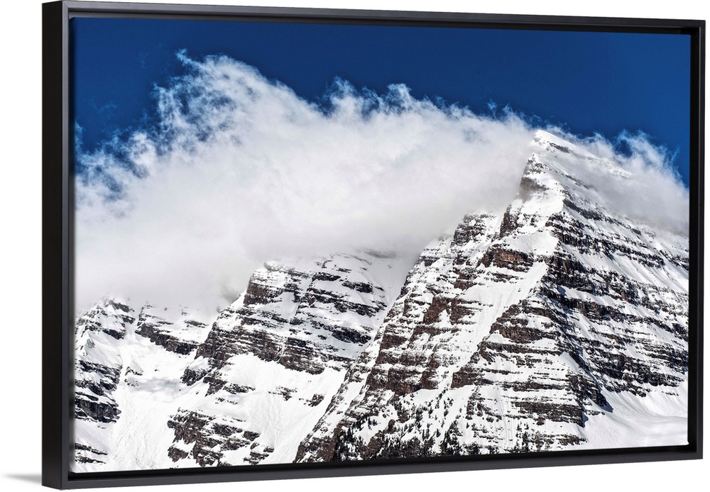 Wind-blown snow on the peaks of the Maroon Bells under a blue sky in Aspen, Colorado.