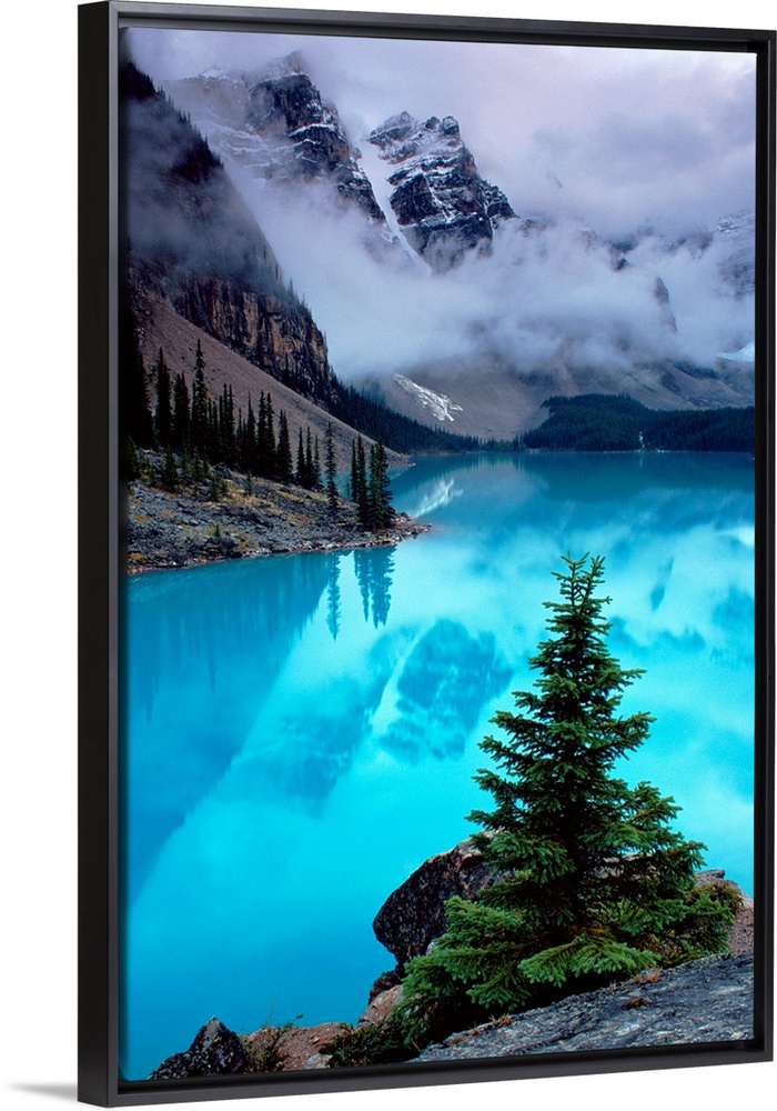 From the National Geographic Collection a photograph of mountains reflecting in water as clouds pass between them; in the ...