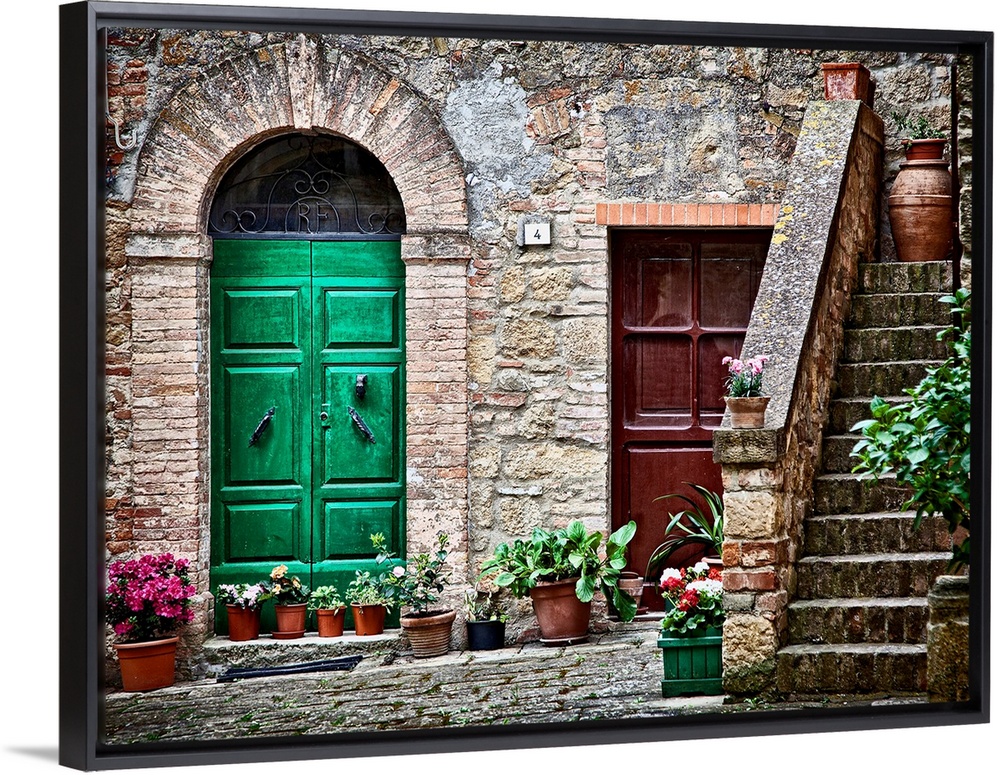 A rustic city street and ancient home built from stone and brick with brightly painted doorways lined with plants in terra...