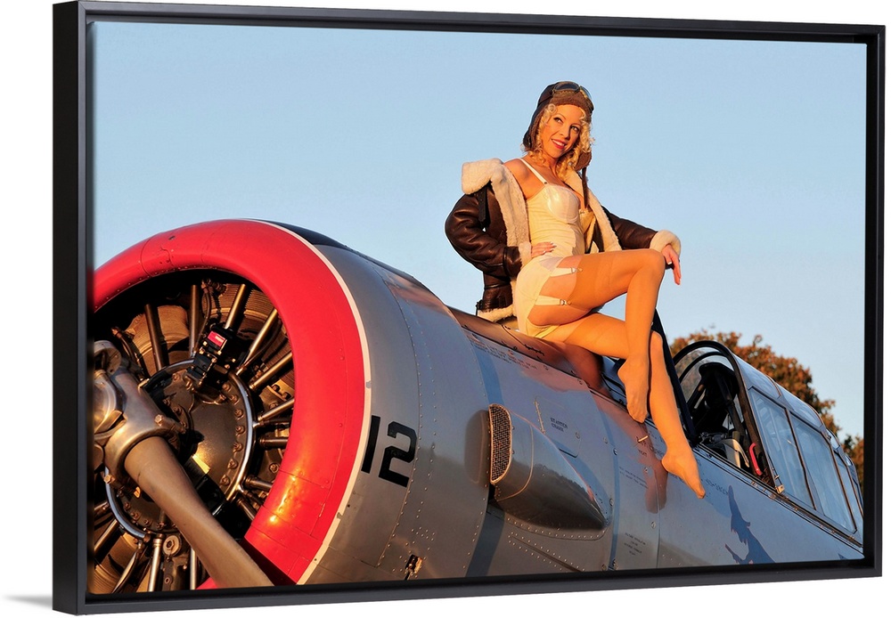 1940's style aviator pin-up girl posing with a vintage World War II T-6 Texan aircraft.