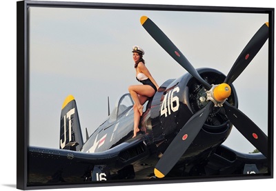 1940's style Navy pin-up girl sitting on a vintage Corsair fighter plane