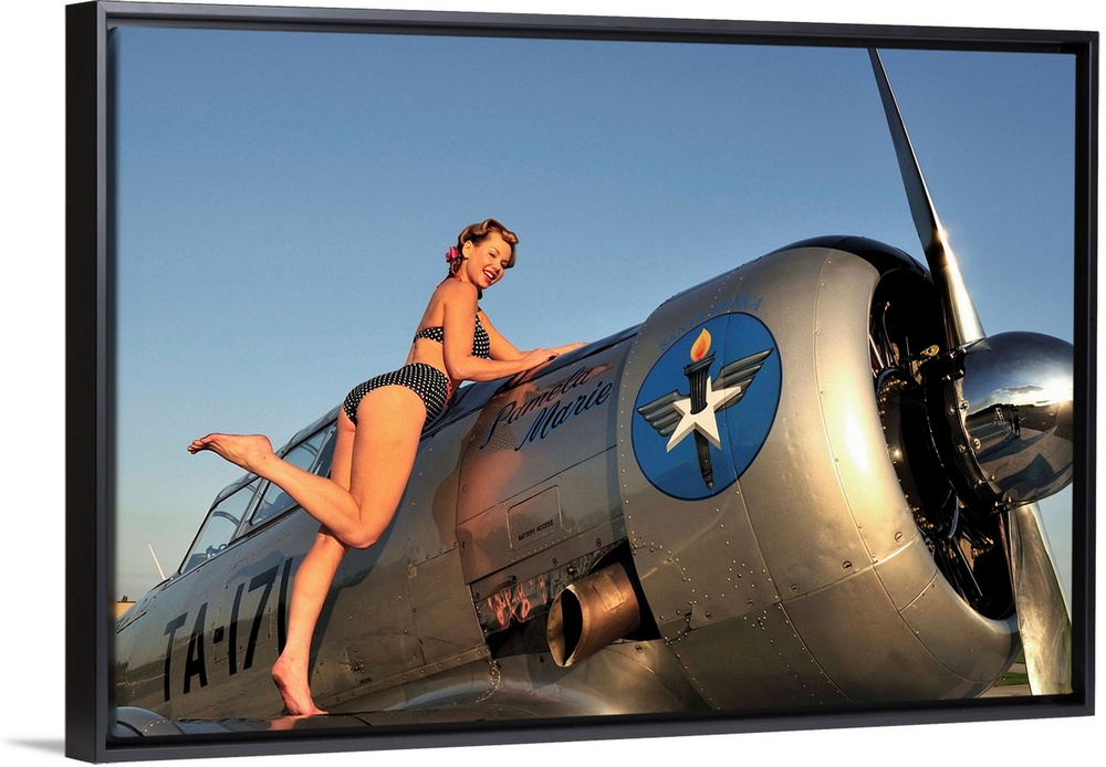 1940's style pin-up girl standing on the wing of a World War II T-6 Texan.