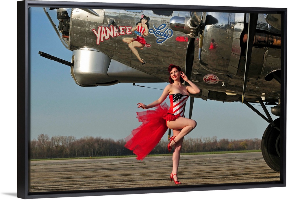 Beautiful 1940's style pin-up girl standing in front of a B-17 bomber.