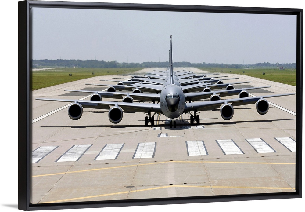 Photograph of several large Stratotanker airplanes perfectly lined up in a row on a runway.