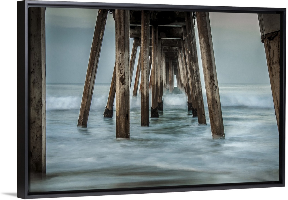 View from below of a wooden pier stretching out into the ocean.