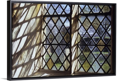 Detail of stone-framed church window with diamond-leaded panes