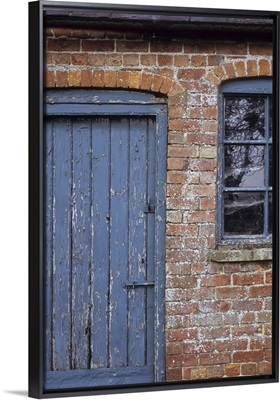 Old orange brick stable block with blue painted wooden door and windows
