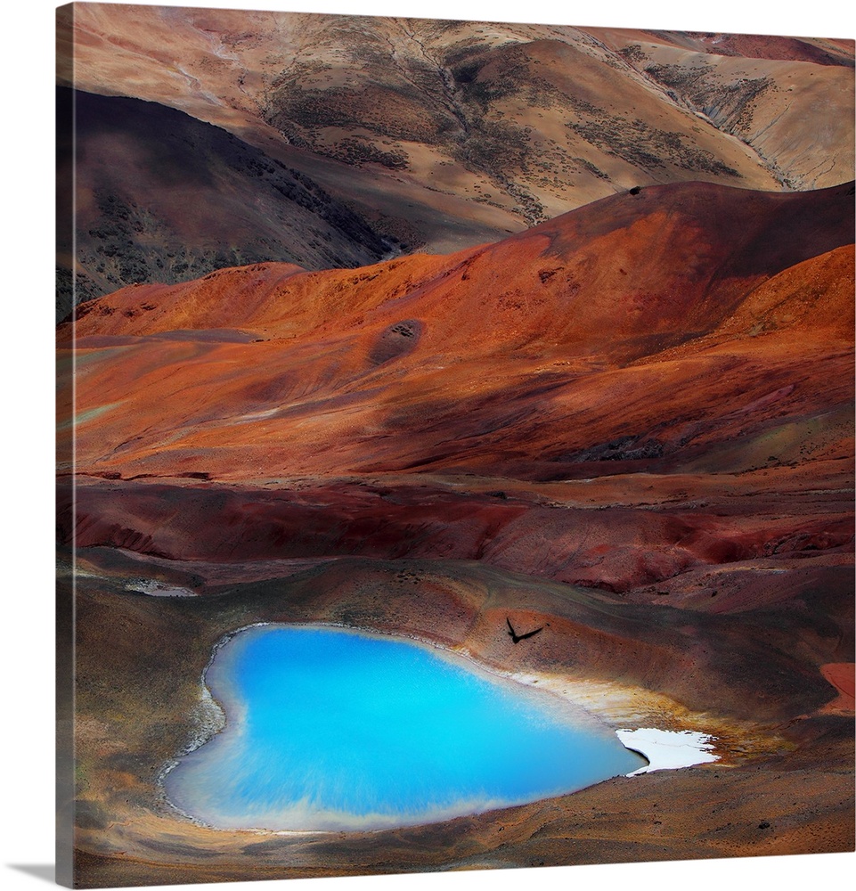 A bright blue heart-shaped lake contrasts with the orange hills of the surrounding desert.