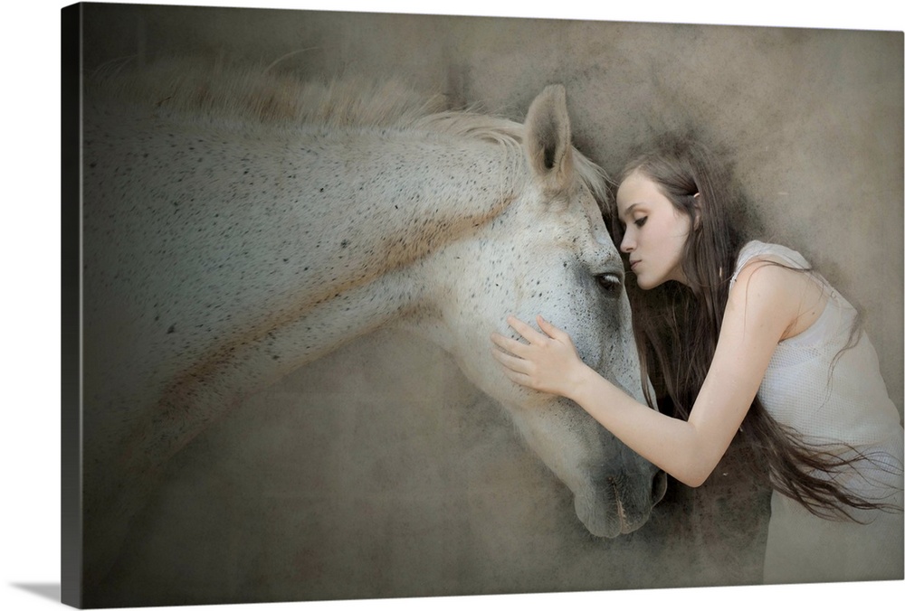 A young woman with long hair leaning forward to kiss a white horse on the forehead.