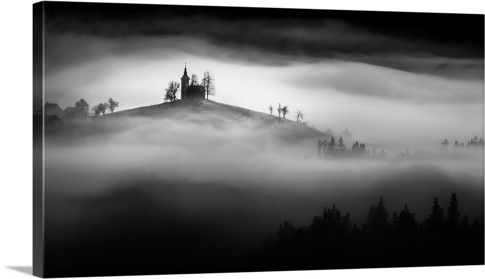 A church perched on a hill in the fog in Slovenia.