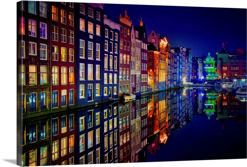 A glowing row of buildings in Amsterdam reflecting in the canal below.