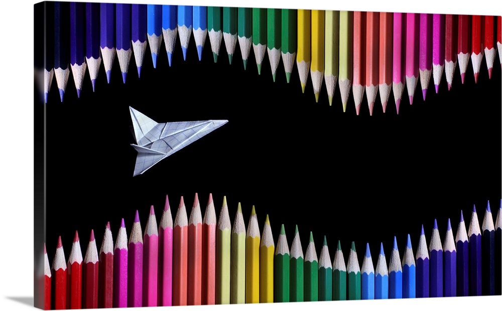 An origami airplane soaring though a sea of colored pencils.