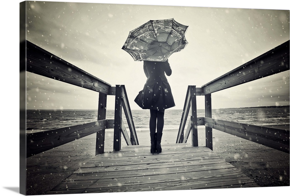Black and white portrait of a woman standing on a wooden pier with a broken umbrella.