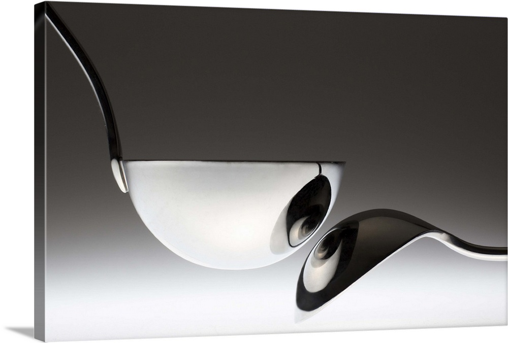 A spoon is reflected in a metal ladle, resembling a pair of eyes.