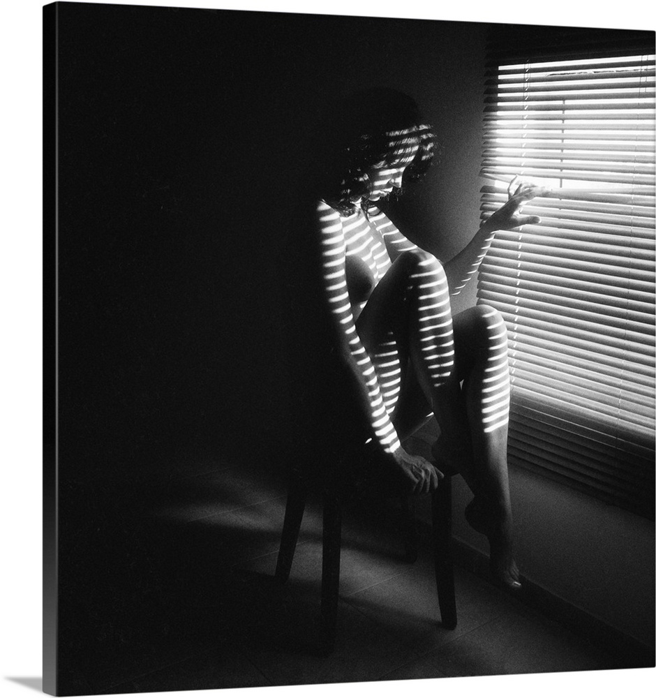 Horizontal bands of light shine through blinds onto the body of a nude woman.