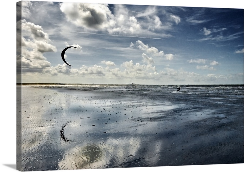 Cool toned photograph of a silhouette of a person kite boarding in the ocean on a beautiful day.