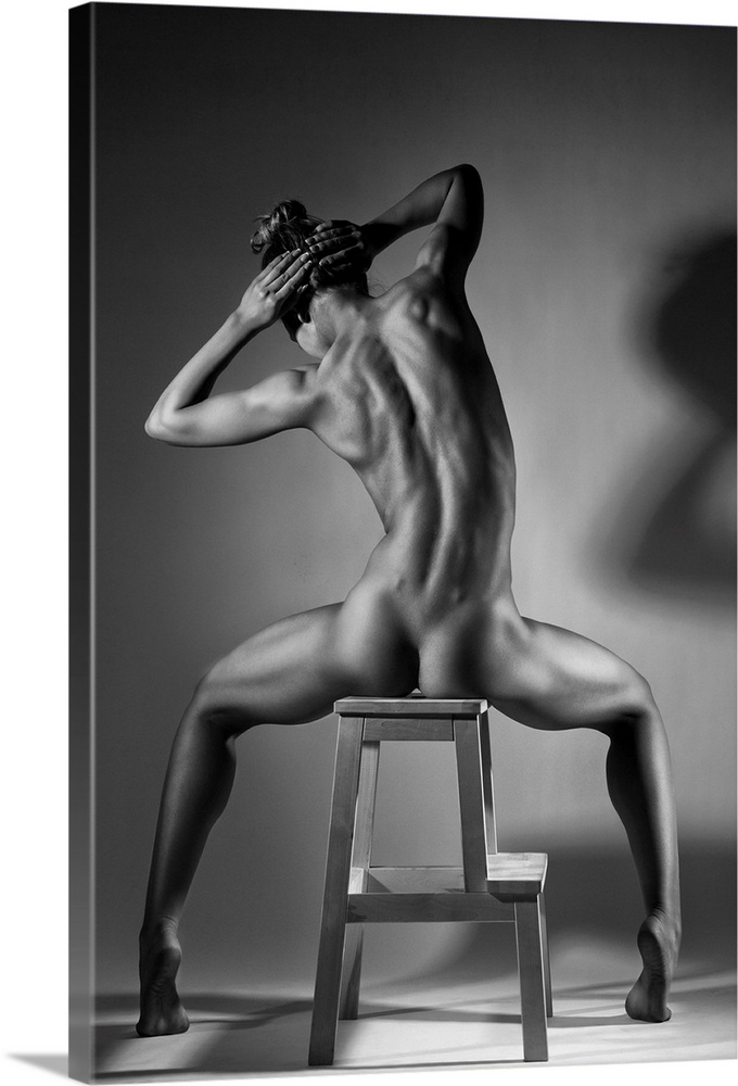 Black and white fine art photograph of a woman with her back to us, sitting in a chair and creating angles with her body.