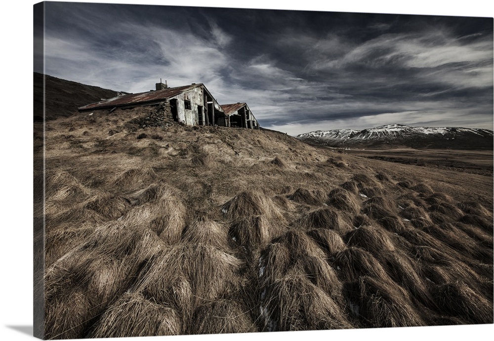 An abandoned farmhouse in Iceland, with mountains in the distance.