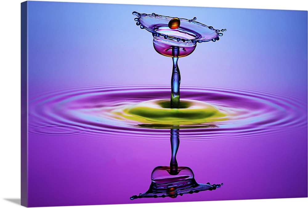 A macro photograph of a tiny water splash caught in mid air and illuminated in vibrant colors.