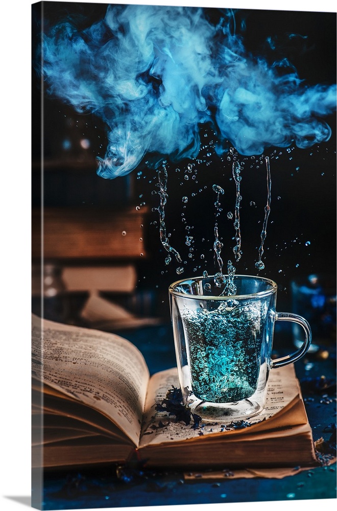 Double wall glass cup of blue tea on an open book under a raining cloud of vapor.