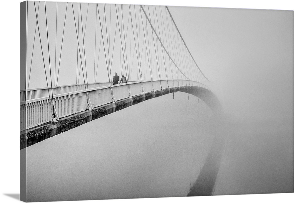 Two people crossing a pedestrian suspension bridge in the winter.
