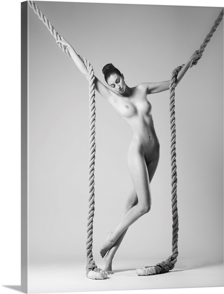 Black and white fine art photograph of a nude woman intertwined with two large ropes.