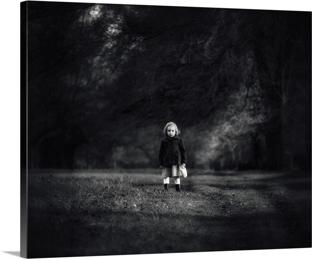 A little girl with a stern expression standing in a field.