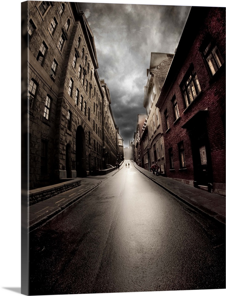 Wide-angle view of a dark street with brick buildings on a cloudy day.