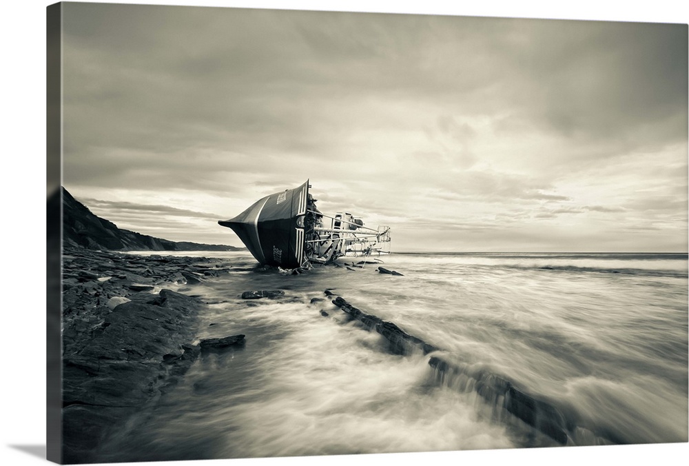 A beached boat laying on its side on the shore.