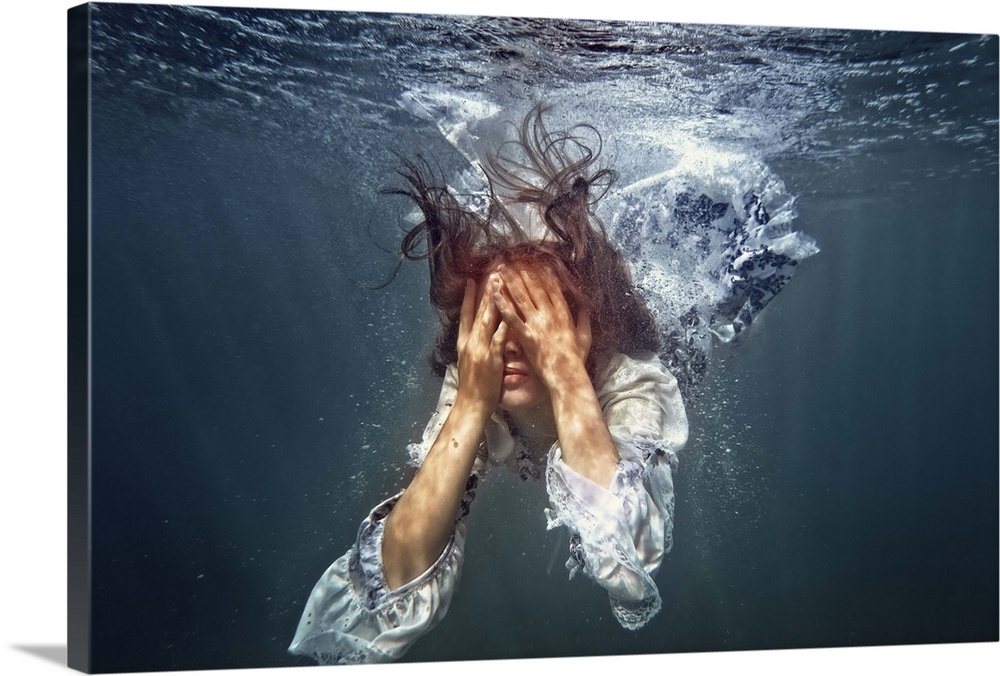 A woman underwater in a white dress with her hands over her eyes.