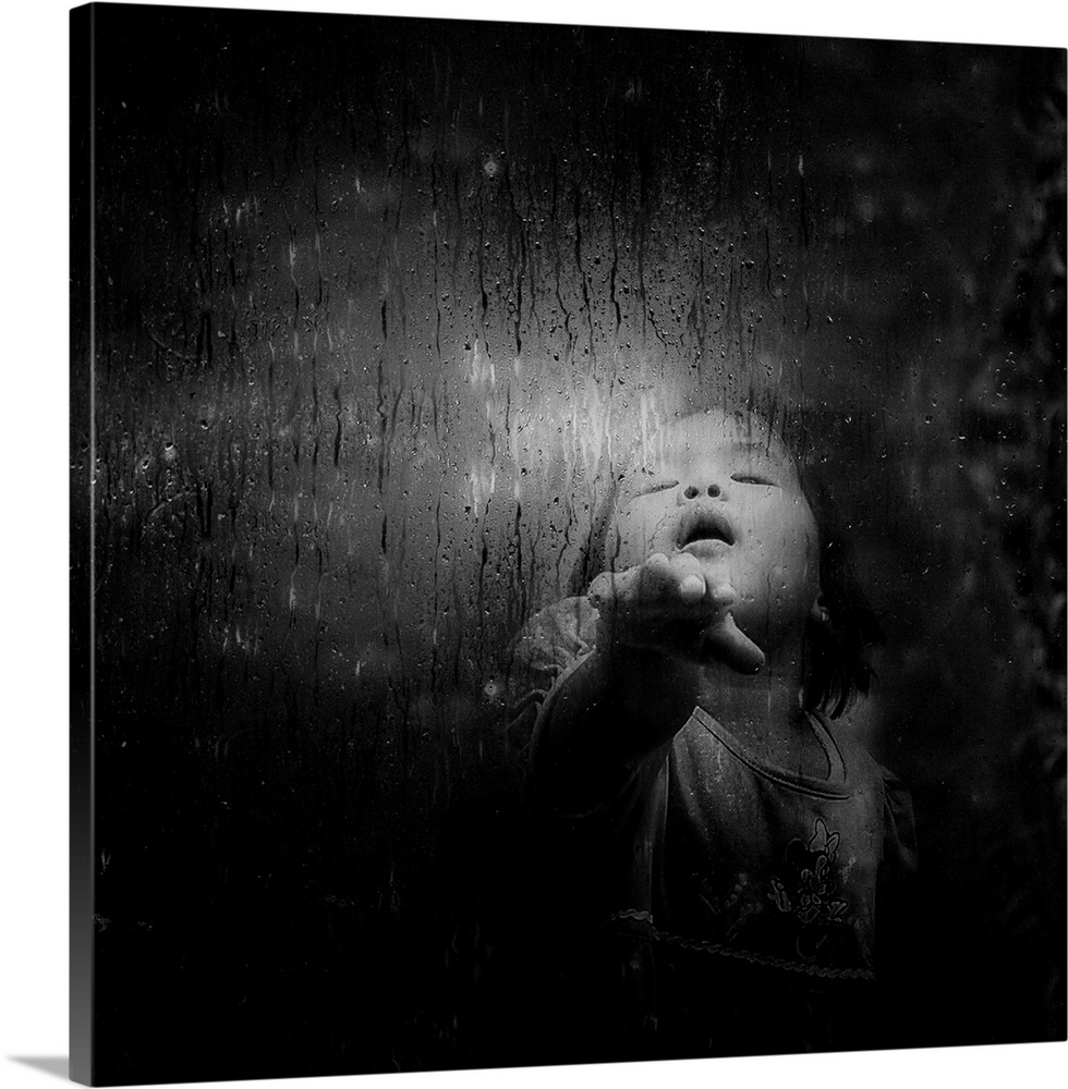 A young child puts her hand against a window with rain and condensation.