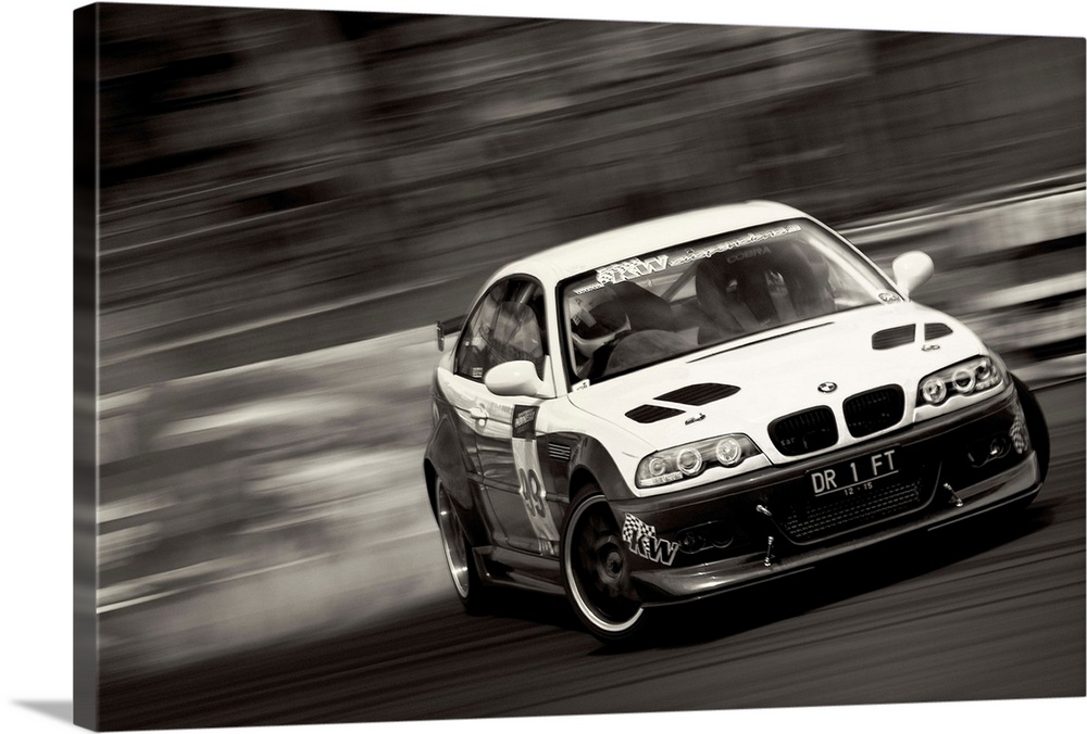A black and white photograph of a sports car drifting against a blurred background.