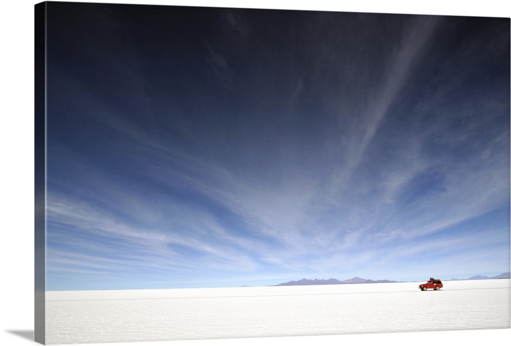 A red car traverses the Salar de Uyuni in Bolivia, a gigantic salt flat.
