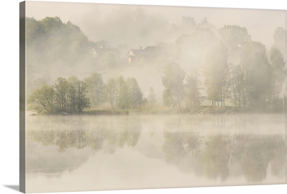 Heavy fog over a lake with houses on the shore, Sweden.