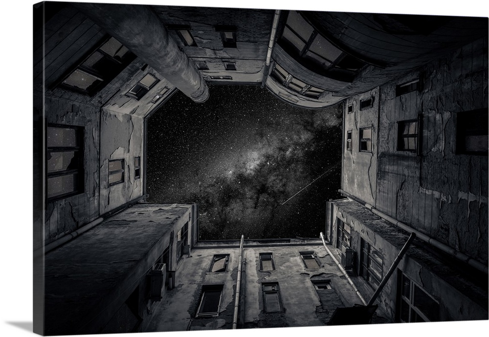 Black and white photograph looking up the walls of a worn courtyard to the starry night sky.