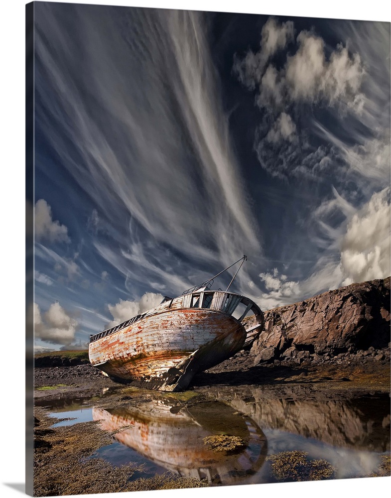 An abandoned and decaying ship beached on land under dramatic clouds in the sky.