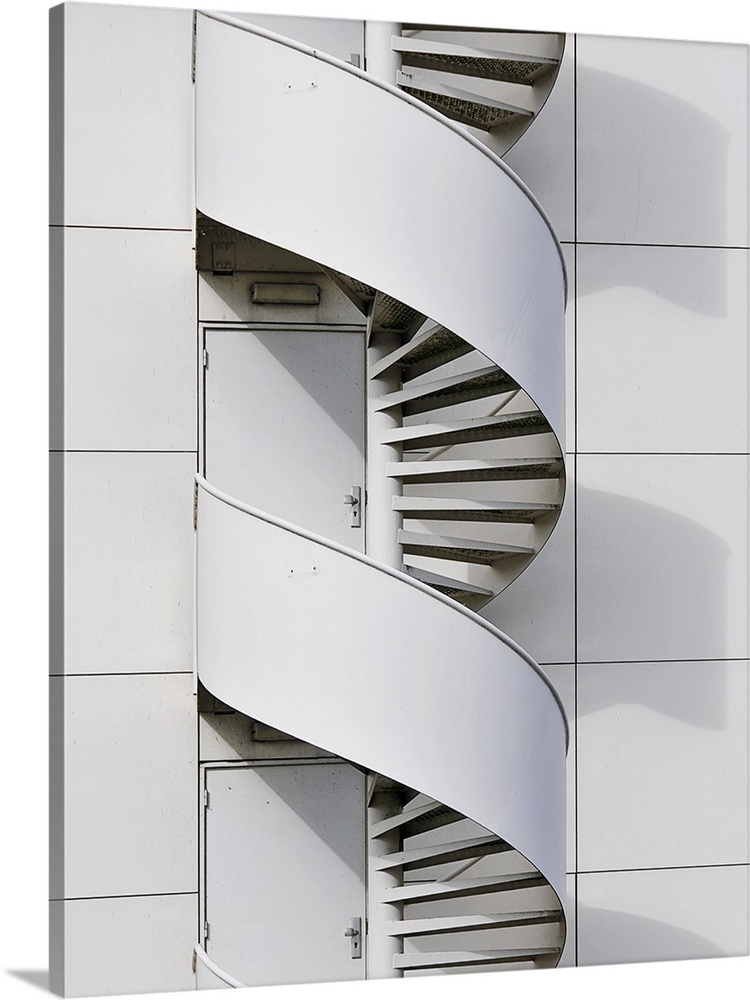 Geometric photograph of a swirly fire escape running along the side of a white building.
