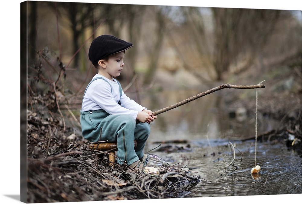 Portrait of a young boy at the edge of a stream with a simple fishing rod.