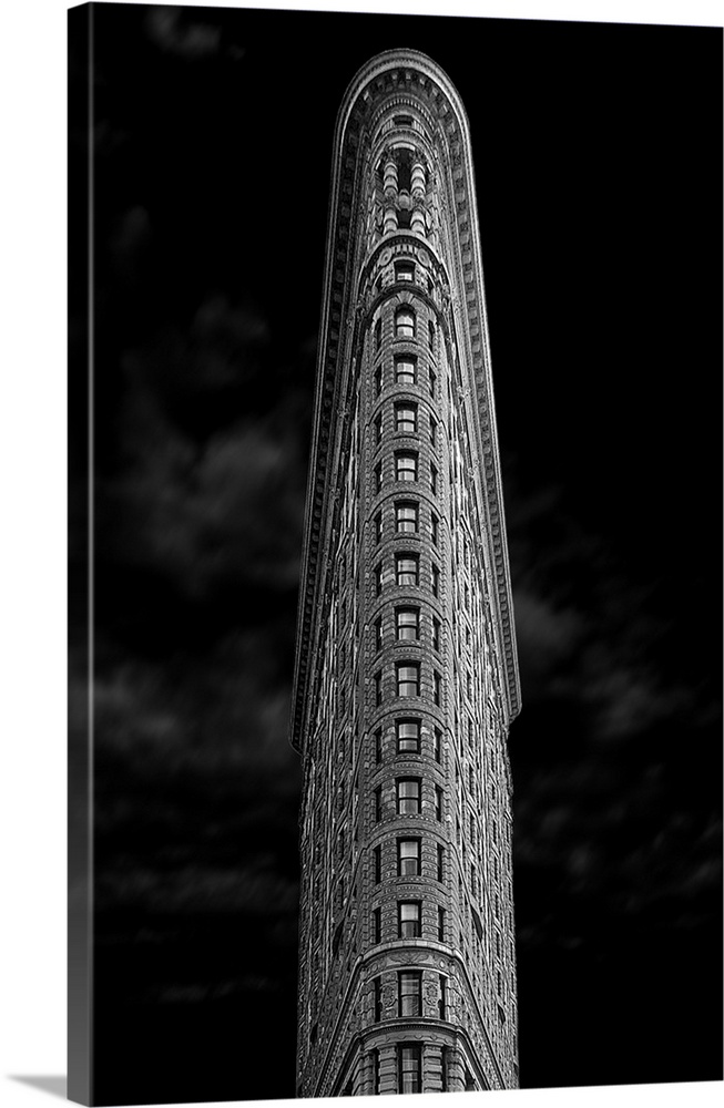 Dramatic view of the Flatiron Building with dark skies above in New York City.