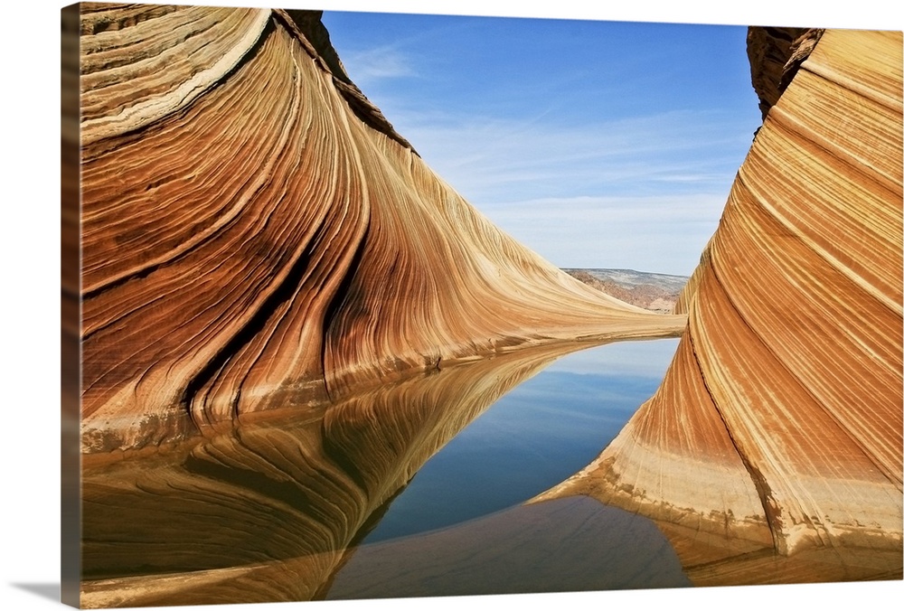 Striated rock formations in Vermilion Cliffs National Monument, reflected in the water of a stream.